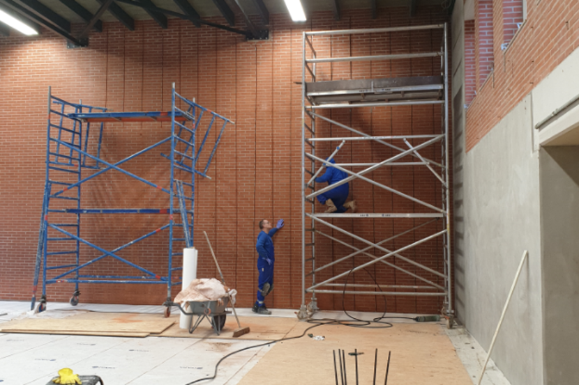Bouwvakkers werken in een gymzaal
