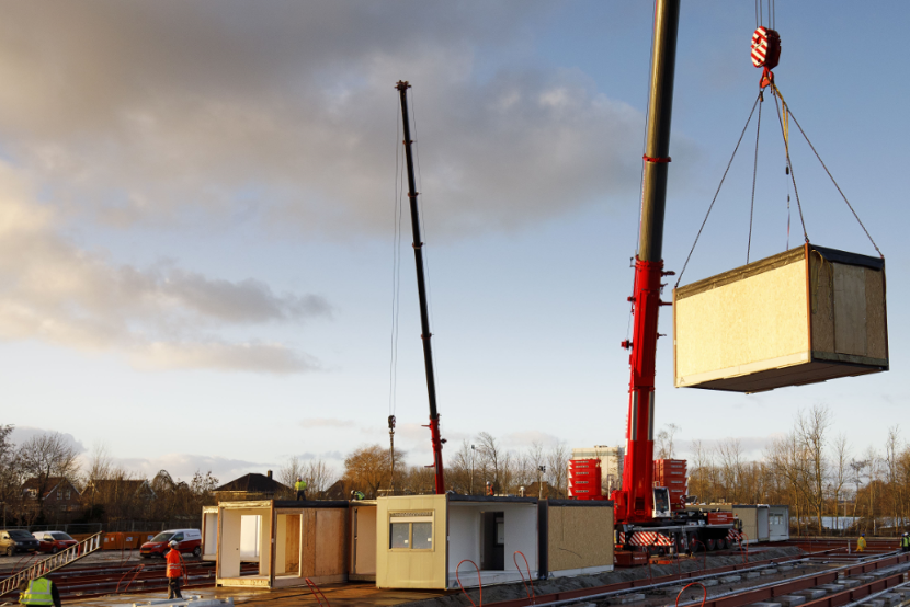 Kraan plaatst module op bouwplaats