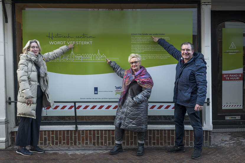Drie personen staan voor een raam met de sticker Historisch Centrum Appingedam wordt versterkt